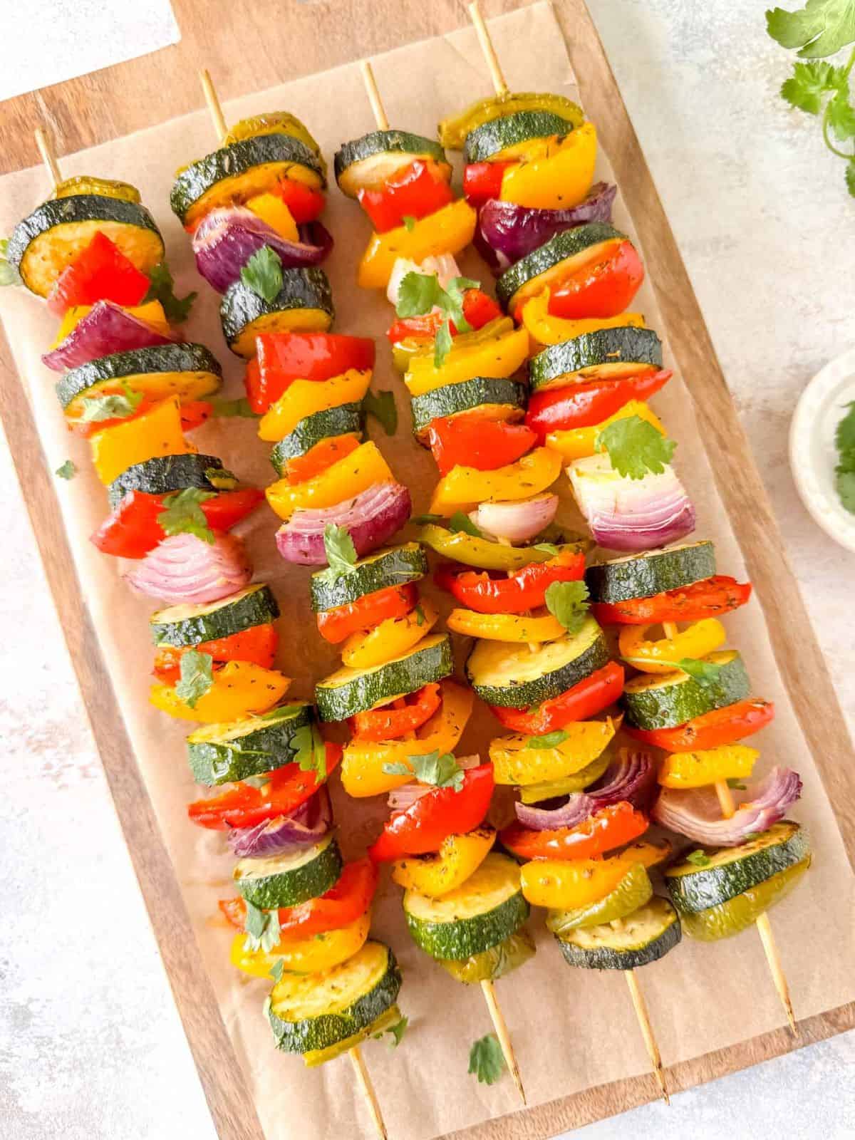 oven baked vegetable kabobs on a wooden board.