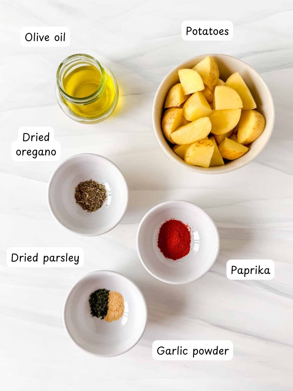 individually labelled bowls of potatoes, olive oil, dried oregano, dried parsley, paprika and garlic powder.