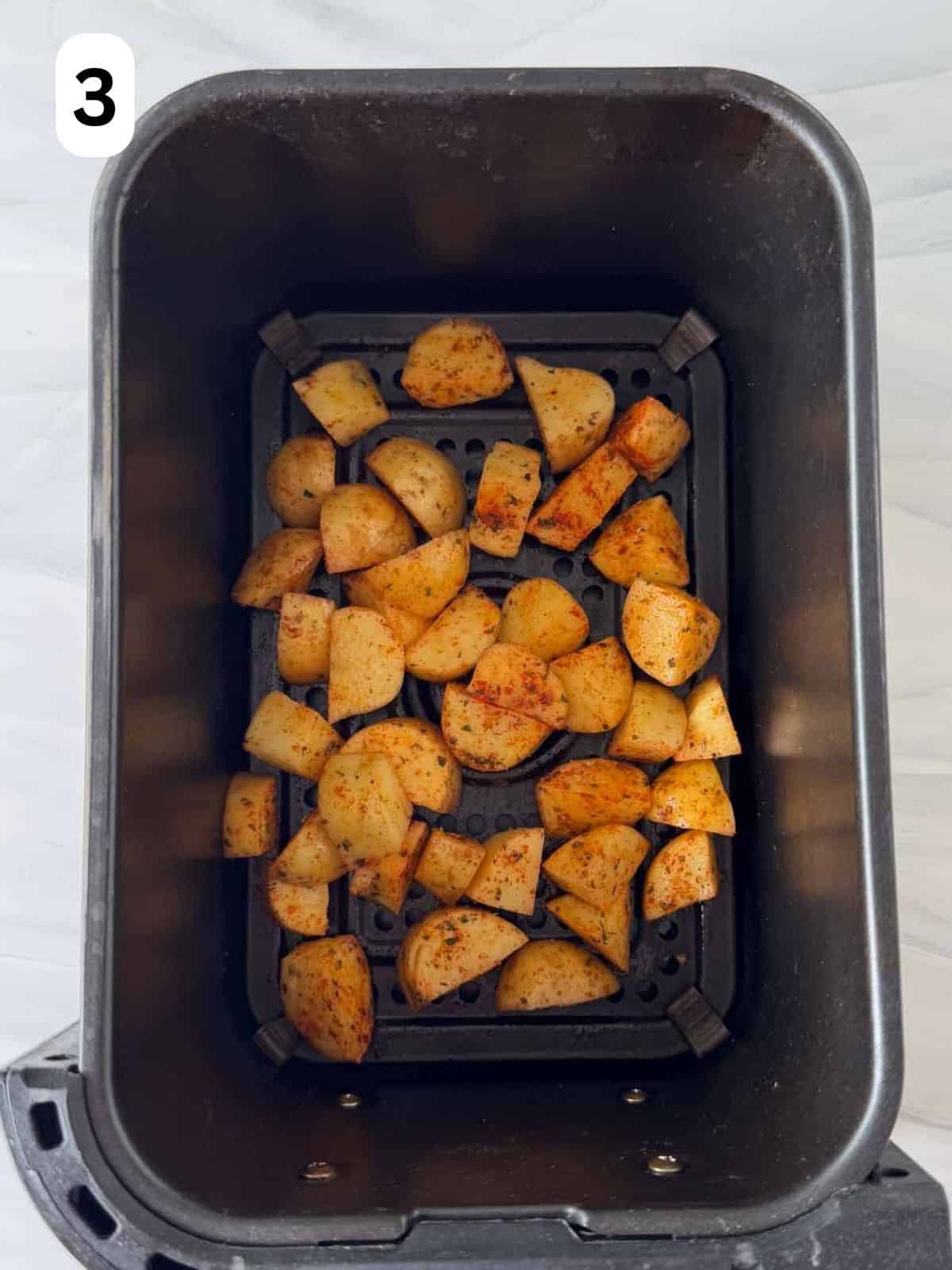 seasoned diced potatoes in an air fryer basket labelled number three.