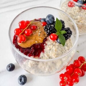 oatmeal chia pudding in a glass topped with fruit, jam and nut butter.