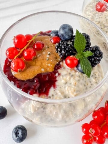 oatmeal chia pudding in a glass topped with fruit, jam and nut butter.