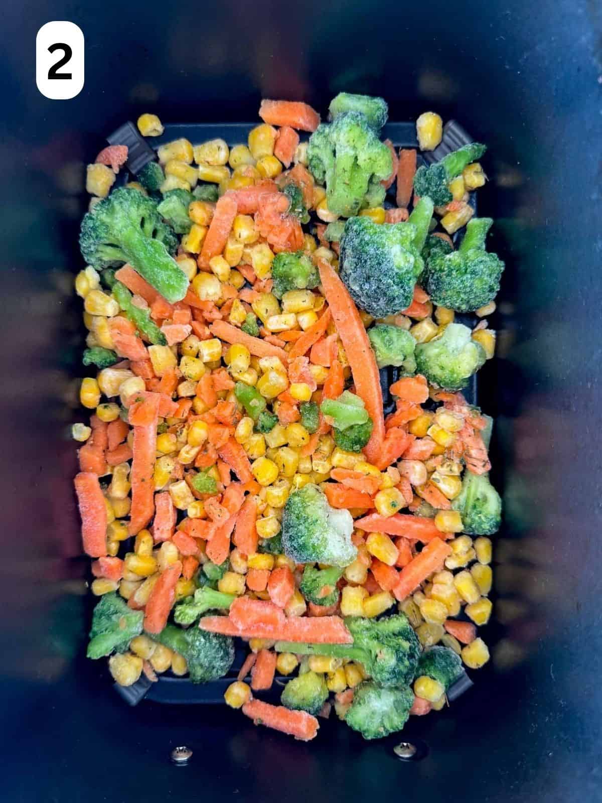 mixed frozen vegetables in an air fryer basket labelled number two.