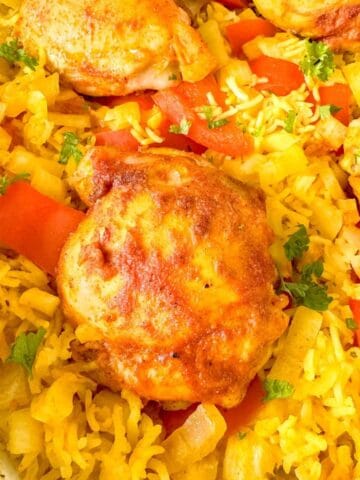 oven baked turmeric chicken and rice in a white casserole dish.