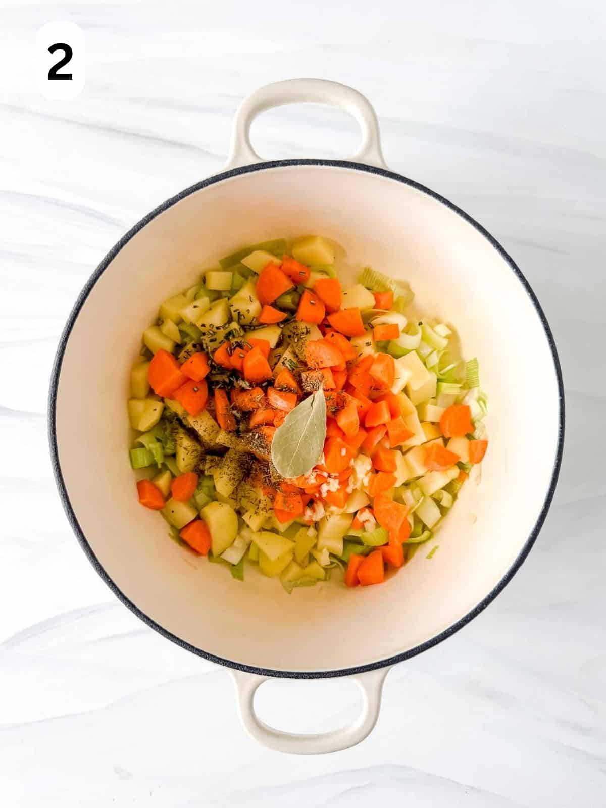 cooked carrots, leeks, potato, garlic, herbs and bay leaf in a white soup pot labelled number two.