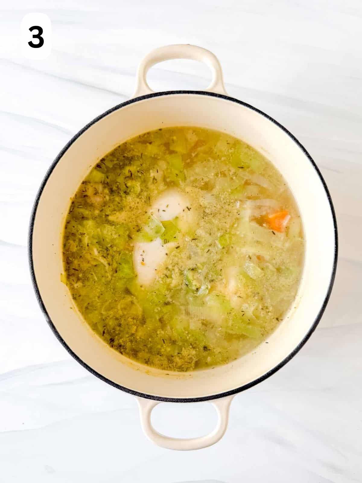 chicken breasts in stock with veggies in a white soup pot labelled number three.