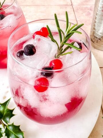cranberry juice mocktails in two glasses next to a cocktail shaker.