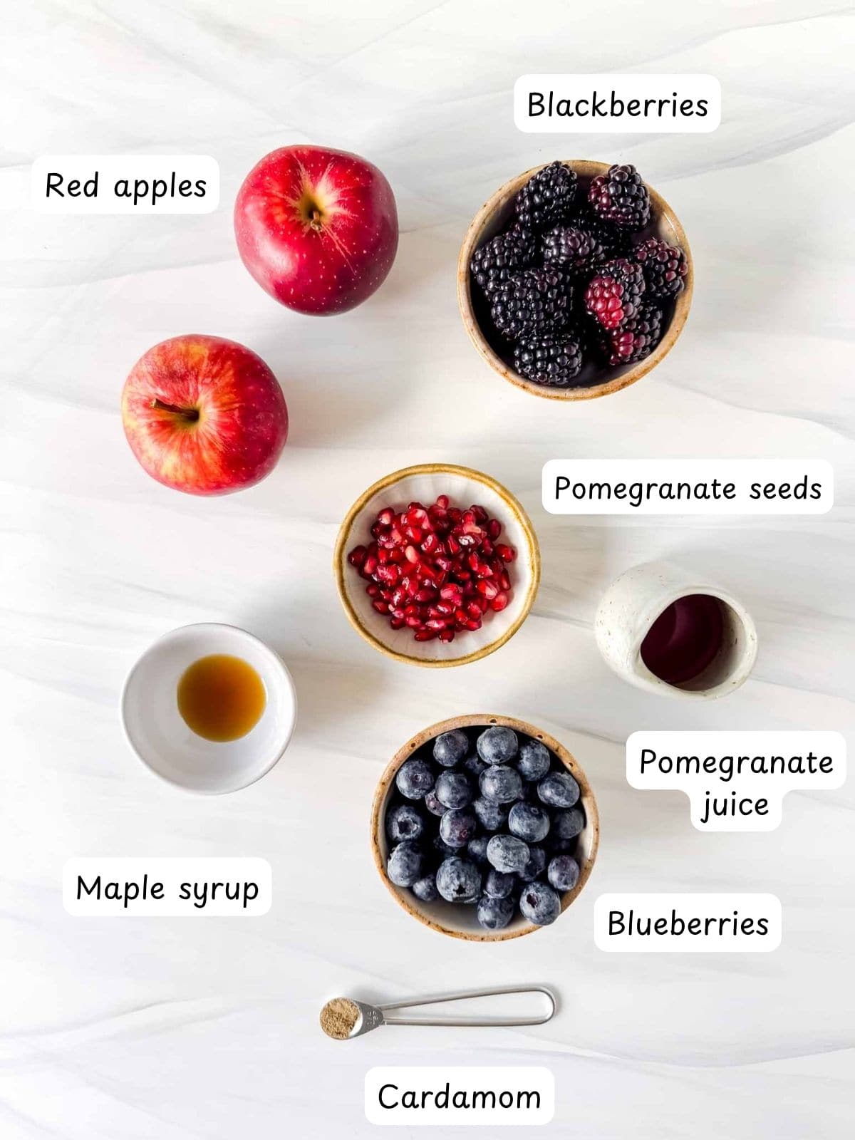 individually labelled red apples, blackberries, pomegranate seeds, blueberries, pomegranate juice, maple syrup and cardamom.
