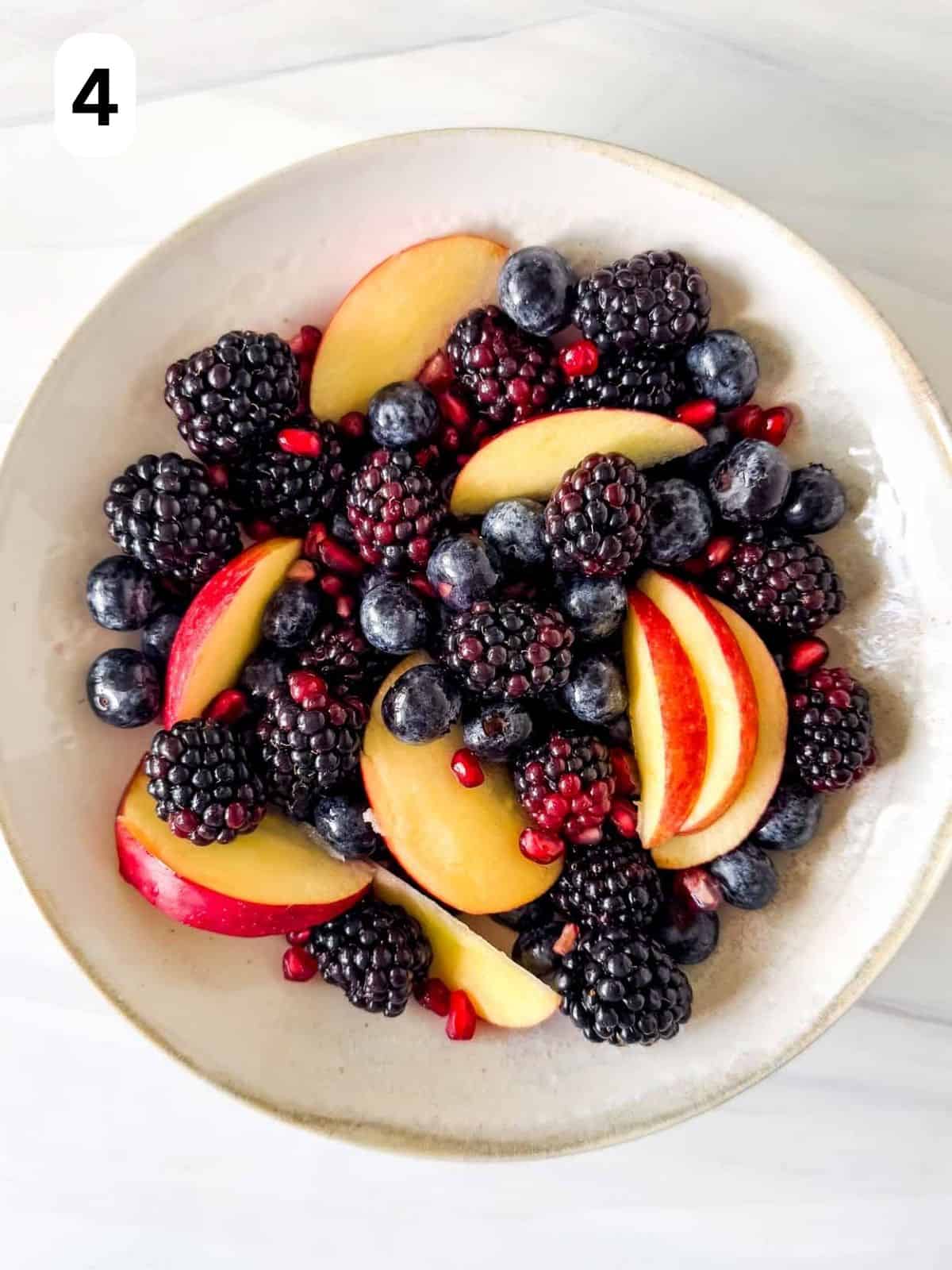 fall fruit salad of red apples, blackberries, pomegranate seeds and blueberries in a bowl labelled number four.