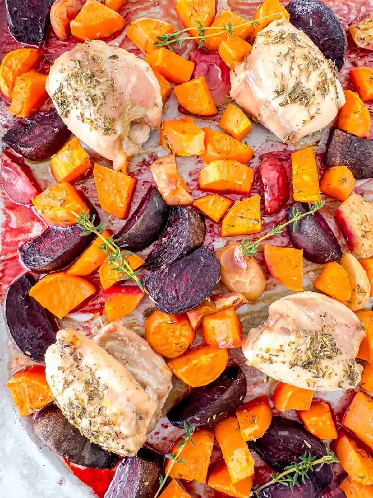 sheet pan chicken and sweet potatoes with beets and apple on a baking sheet.