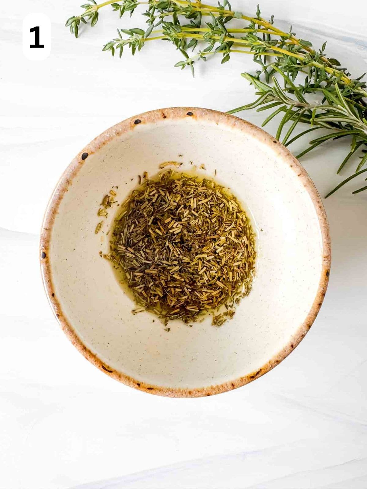 oil and dried herbs in a small bowl next to fresh thyme labelled number one.