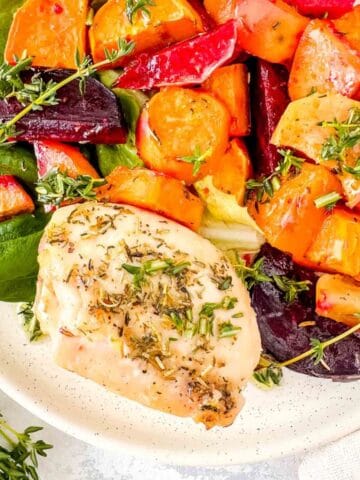 sheet pan chicken and sweet potatoes with beets, apple and lettuce on a white plate.