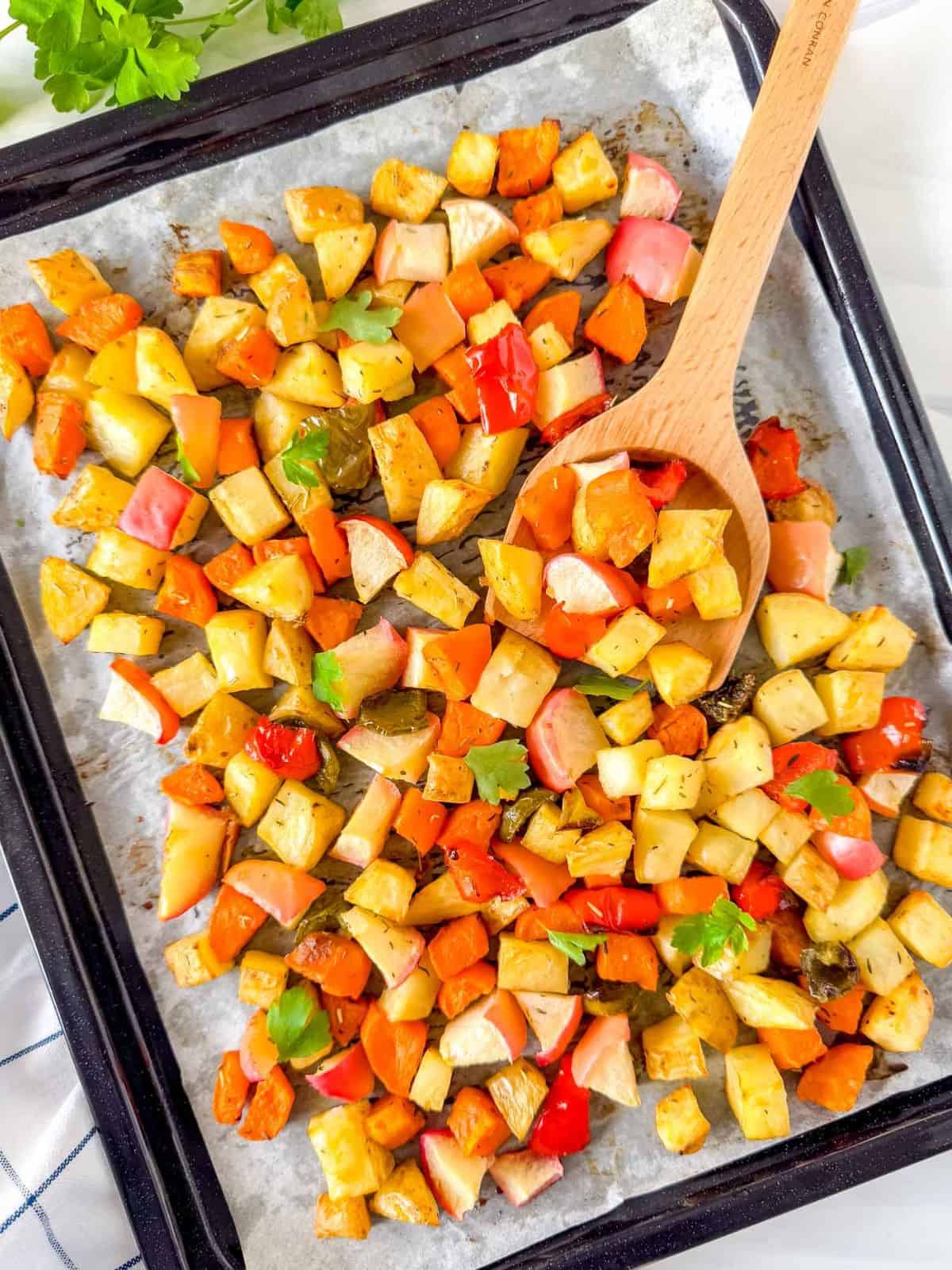 sweet potato and potato hash on a sheet pan next to fresh parsley.