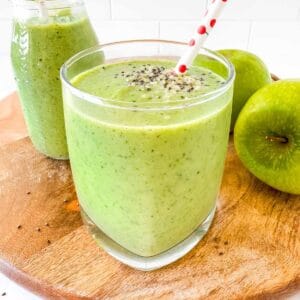 apple kale smoothie in a glass next to green apples.