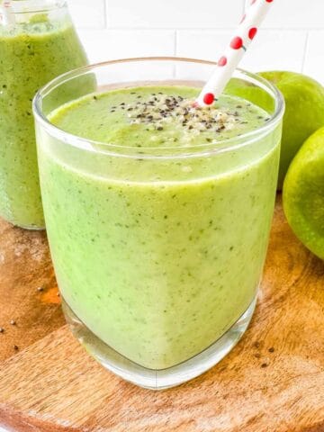 apple kale smoothie in a glass next to green apples.