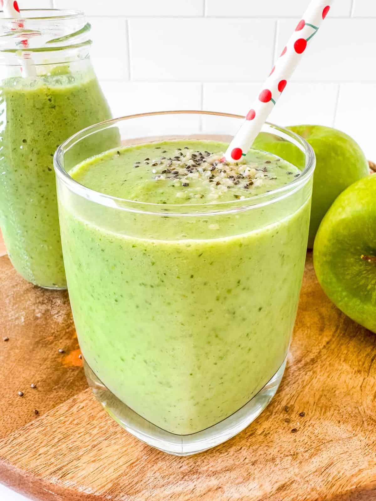 apple kale smoothie in two glasses next to green apples.