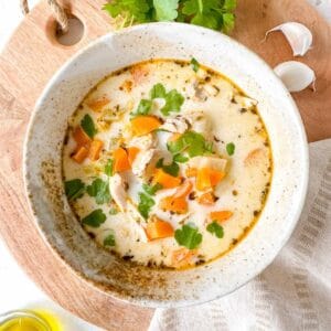 dairy free creamy chicken soup in a bowl next to fresh parsley and garlic cloves.