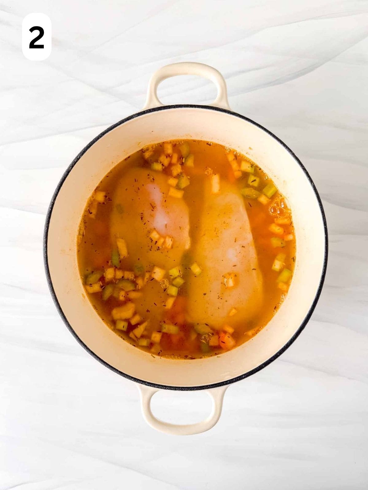 chicken breasts being poached in stock with vegetables in a soup pot labelled number two.