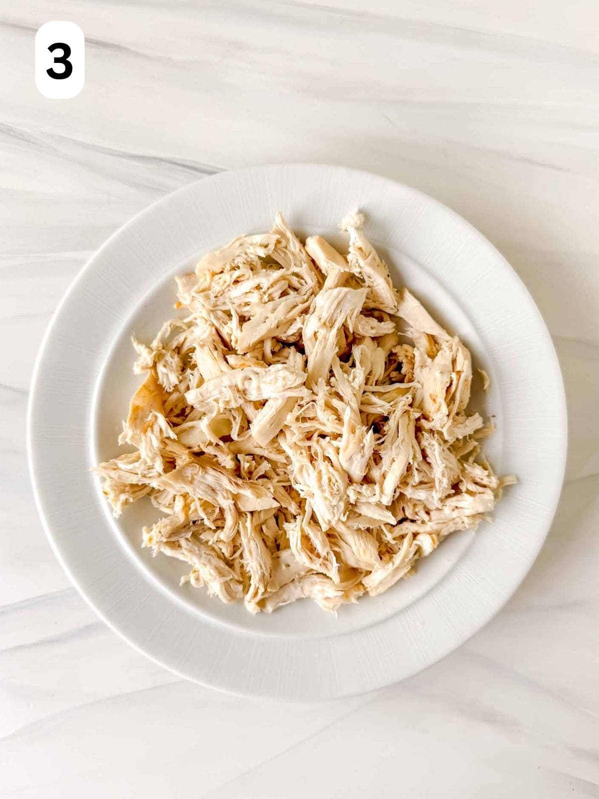 shredded chicken on a white plate labelled number three.