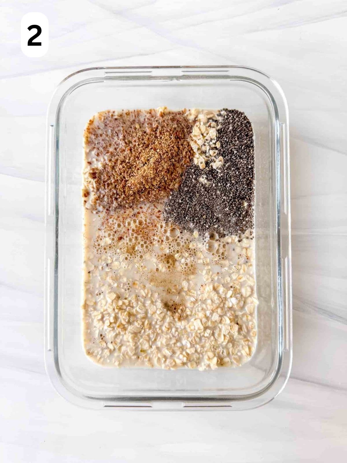 rolled oats, ground flaxseed, chia seeds, cardamom, non dairy milk and maple syrup in a glass container labelled number two.