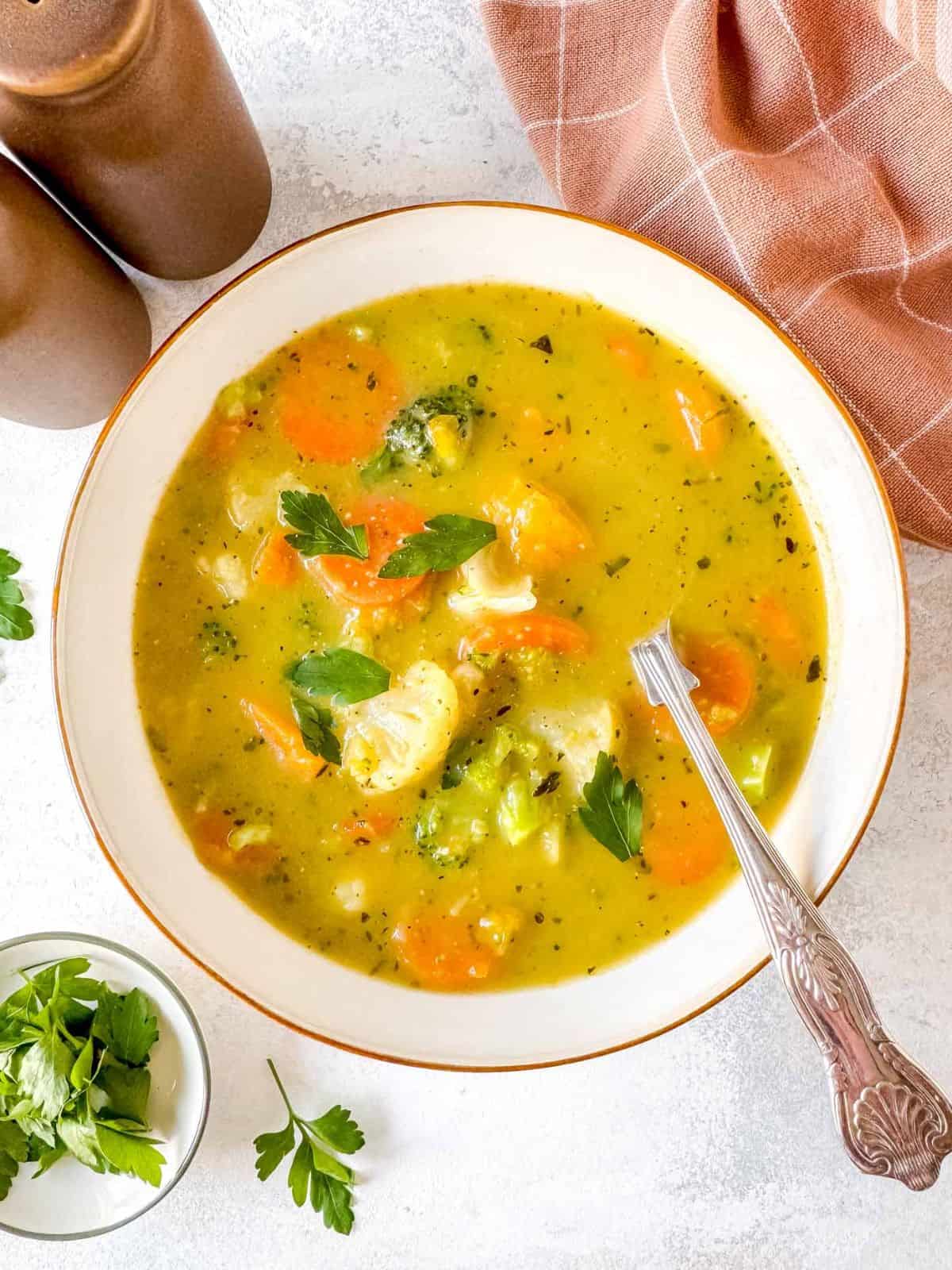 frozen vegetable soup in a white bowl garnished with fresh parsley.