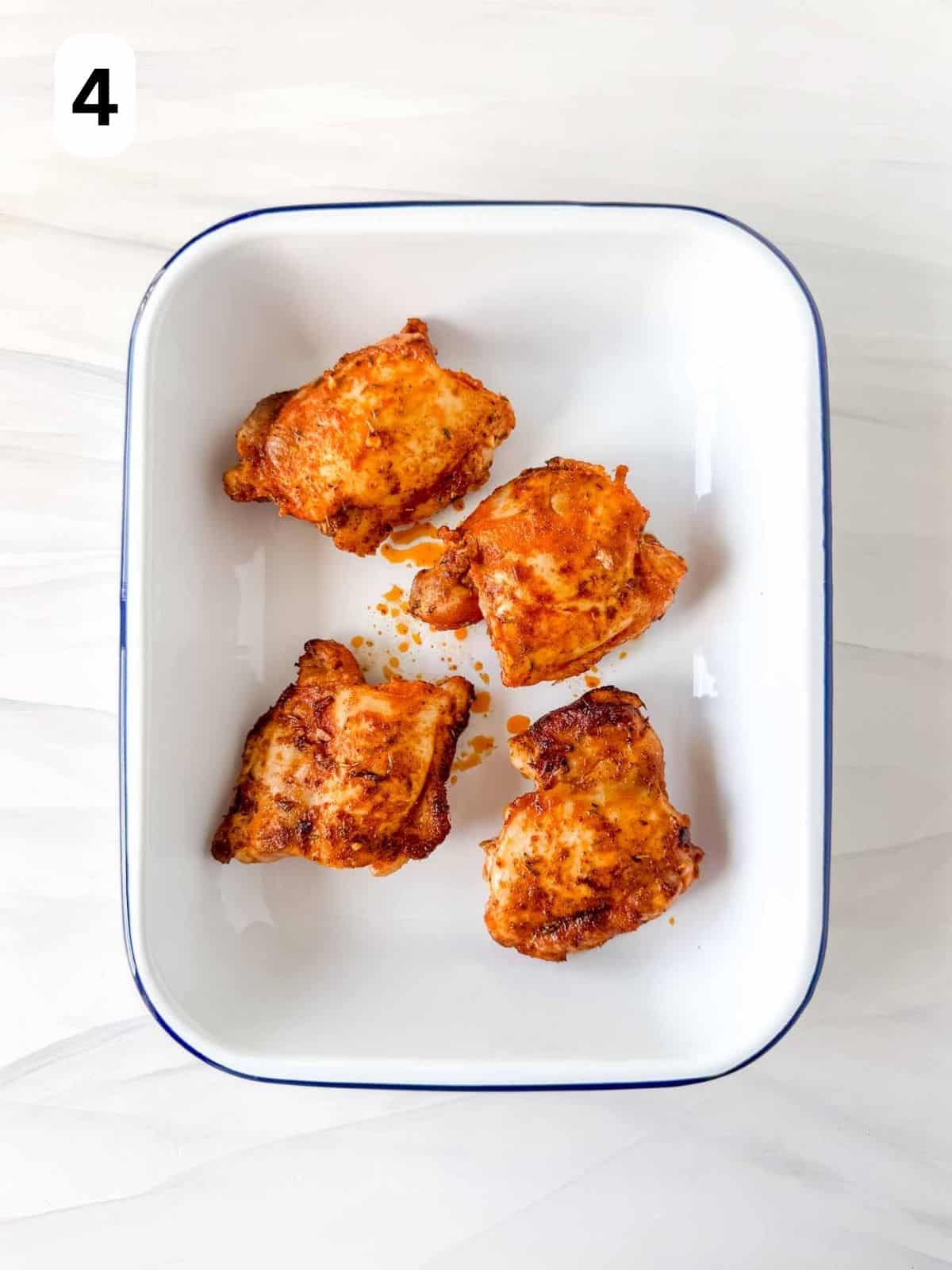 four chicken thighs with paprika in an ovenproof dish labelled number four.