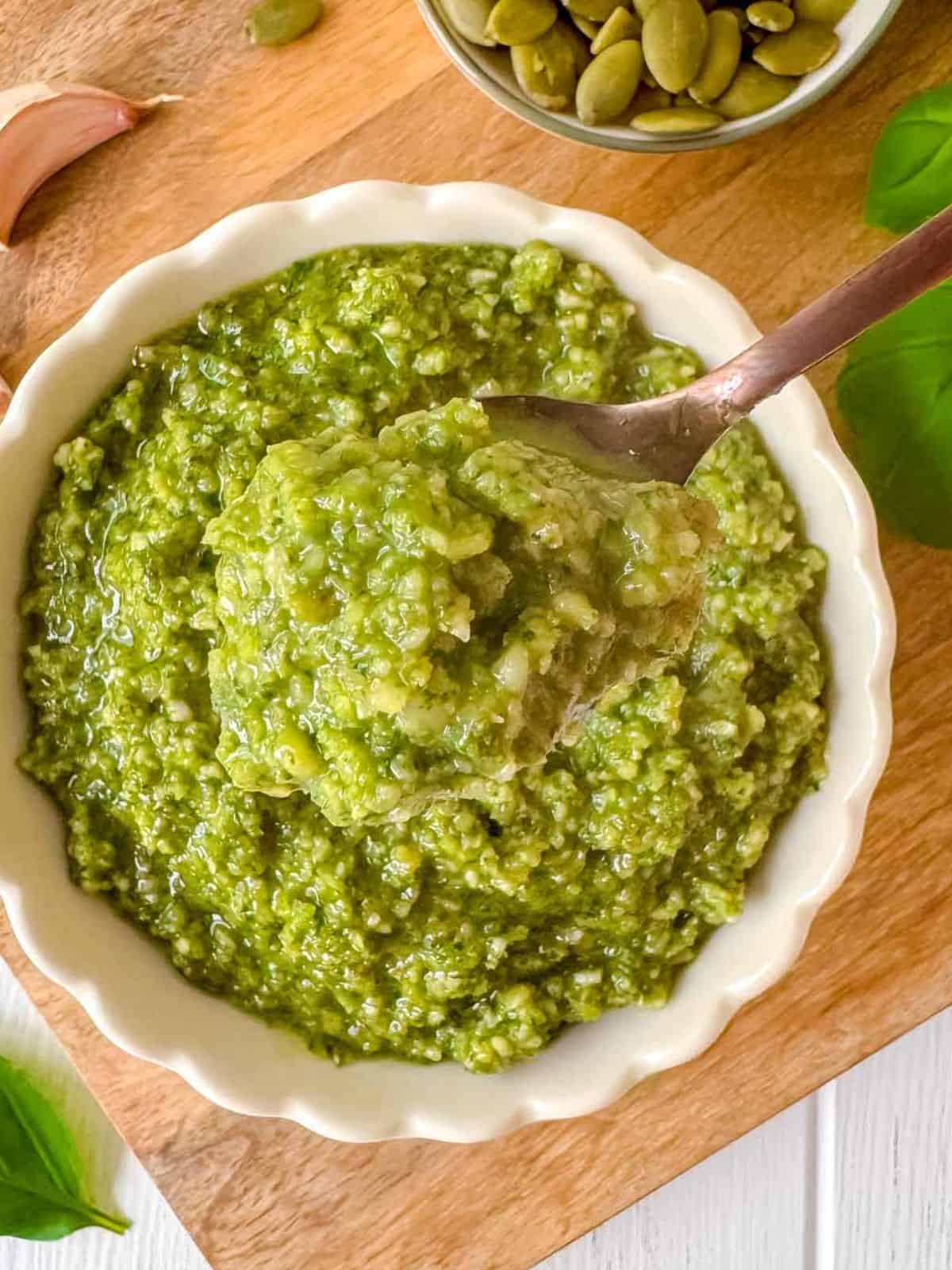 pumpkin seed pesto in a bowl with a spoonful of pesto held above it.