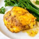 cardamom chicken thigh on a plate with broccoli and mashed potatoes.