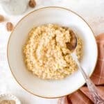 cardamom rice pudding in a white bowl with a spoon in it.