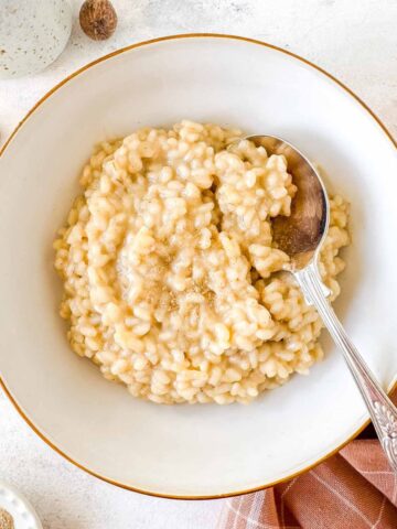 cardamom rice pudding in a white bowl with a spoon in it.