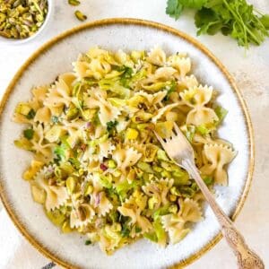 cabbage pasta with leeks and pistachios in a bowl next to fresh parsley.