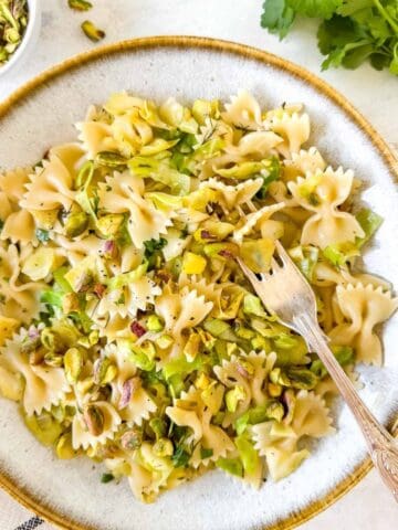 cabbage pasta with leeks and pistachios in a bowl next to fresh parsley.