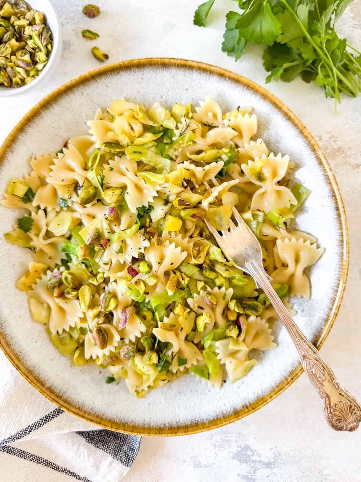 cabbage pasta in a bowl with a fork next to fresh parsley.