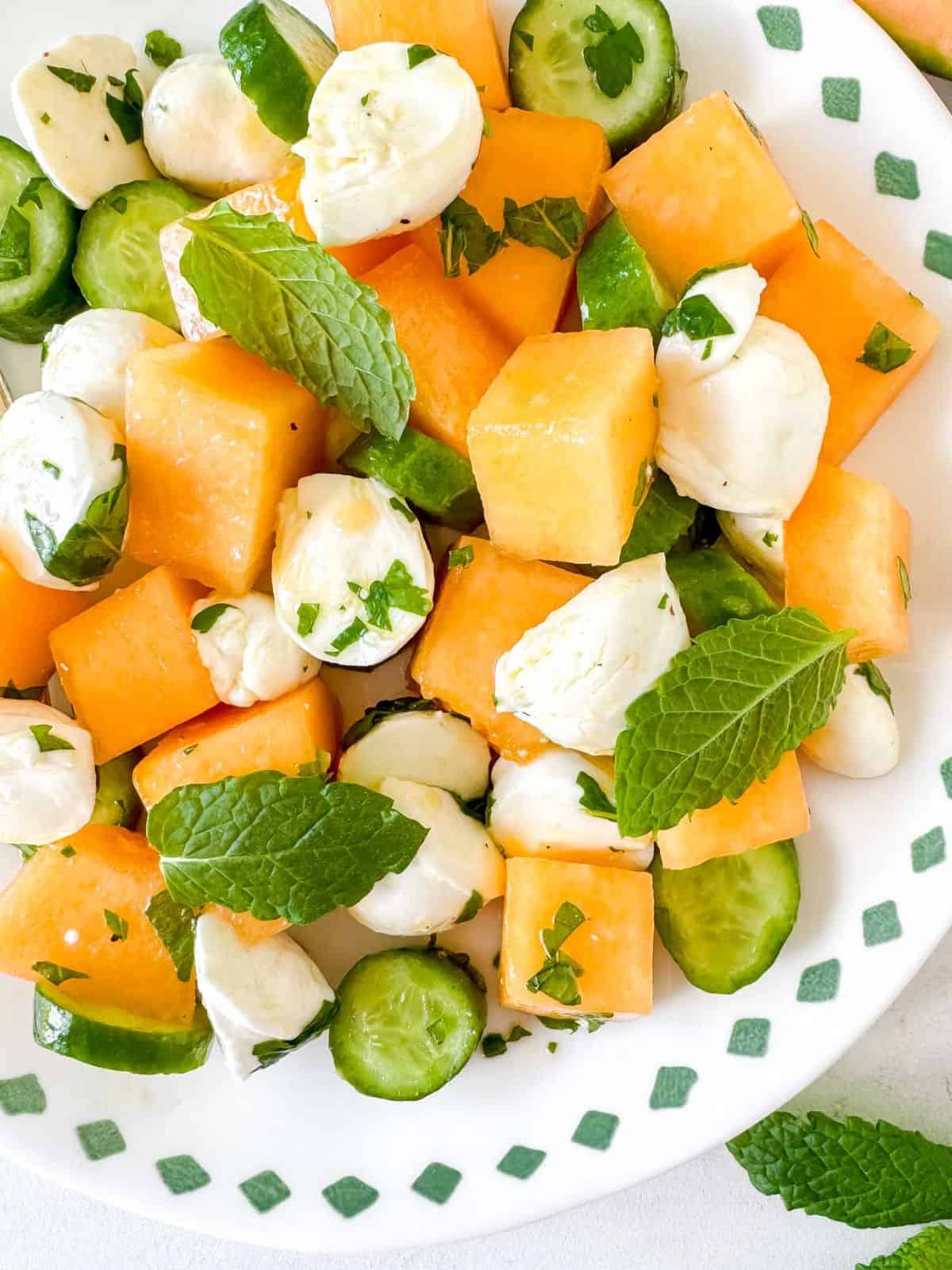 cantaloupe salad garnished with fresh mint on a white plate.