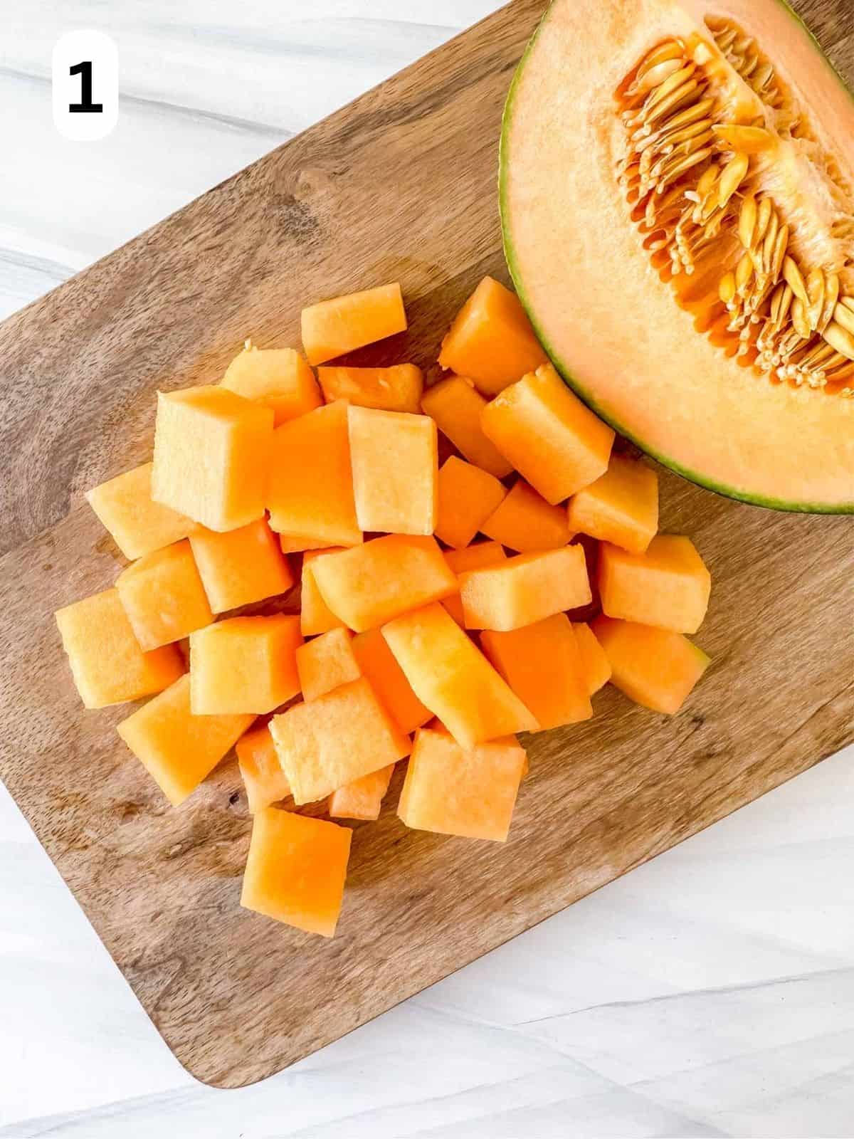 diced cantaloup melon on a wooden chopping board labelled number one.