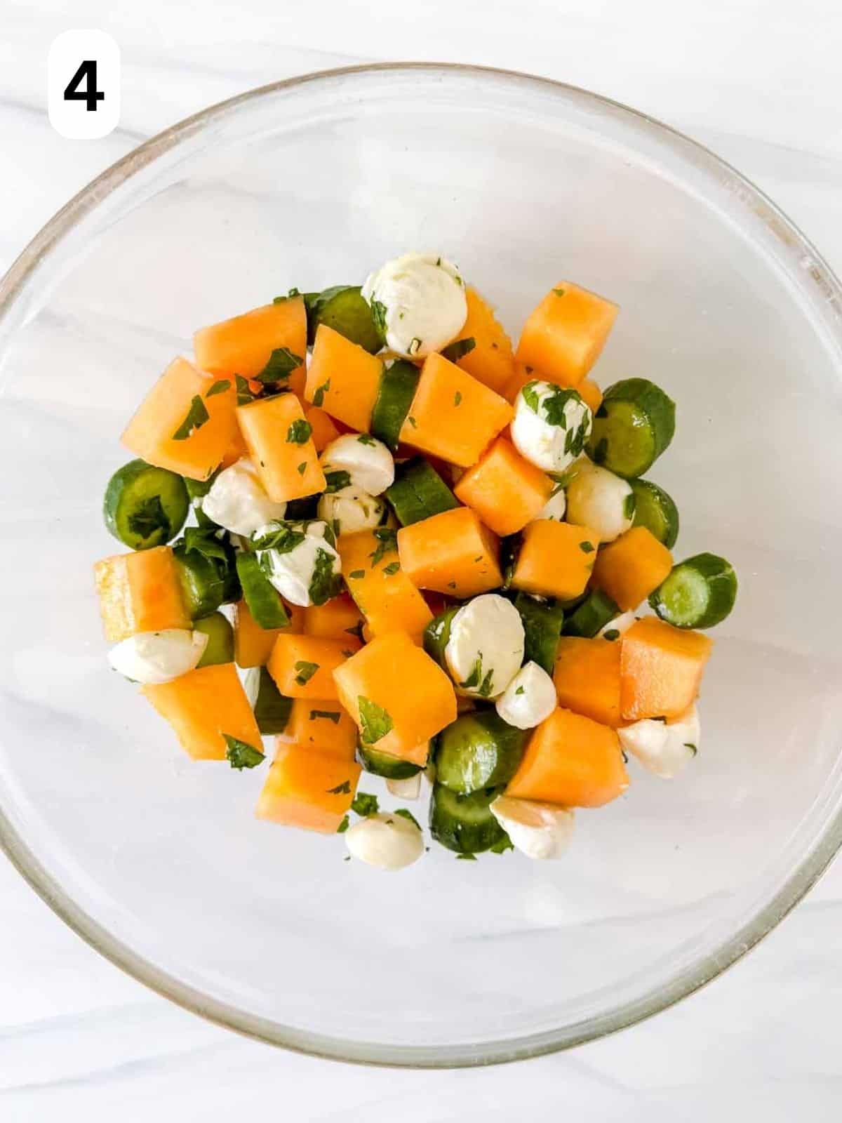 cantaloupe salad with mozzarella, cucumber and mint in a glass bowl labelled number four.