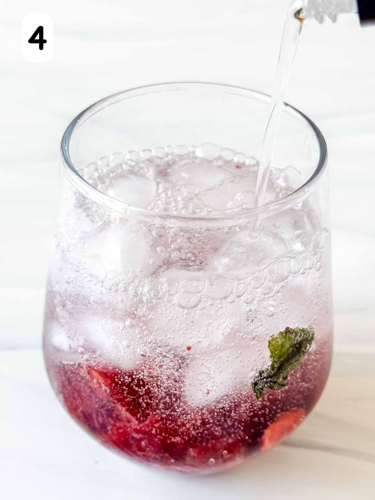 sparkling water being poured into a glass with cherries and ice cubes labelled number four.