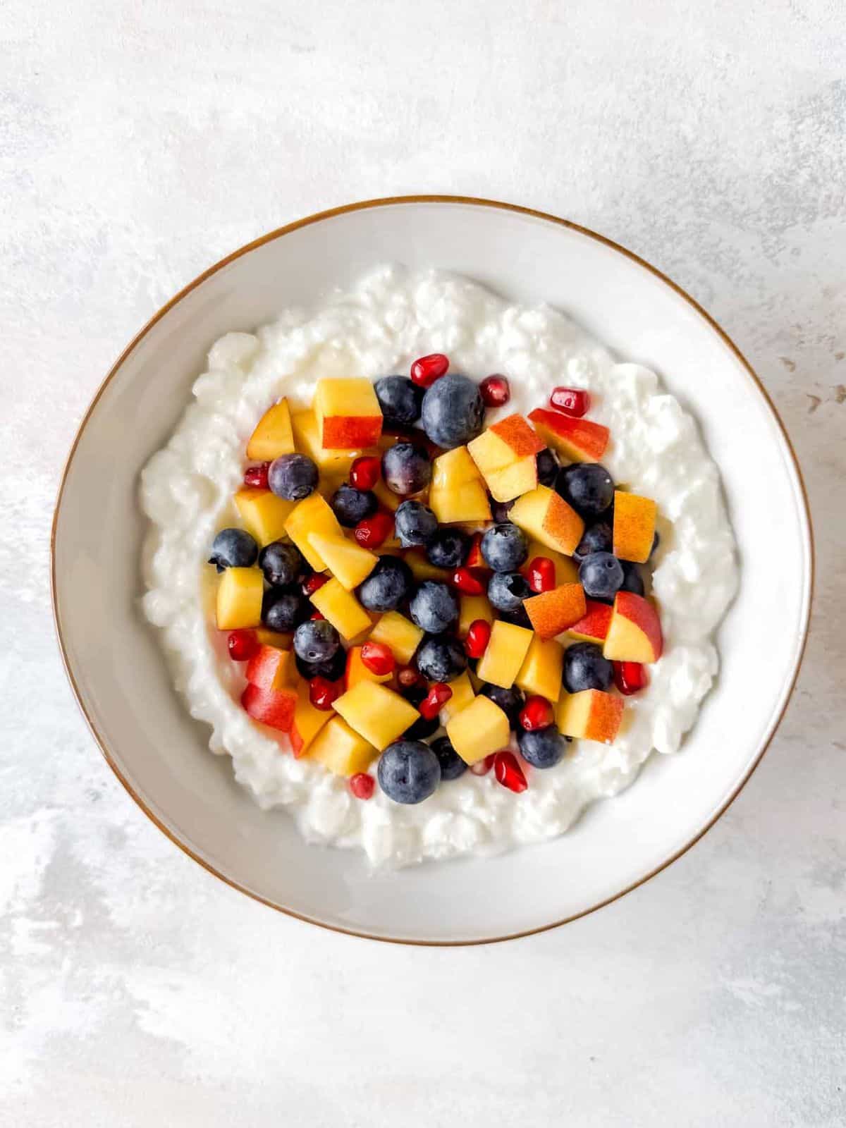 cottage cheese topped with fruit in a white bowl.