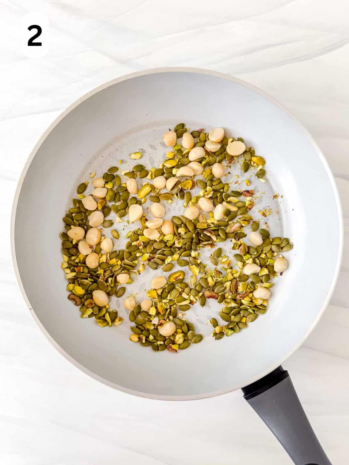 macadamia nuts, pistachios and pumpkin seeds in a dry skillet pan labelled number two.