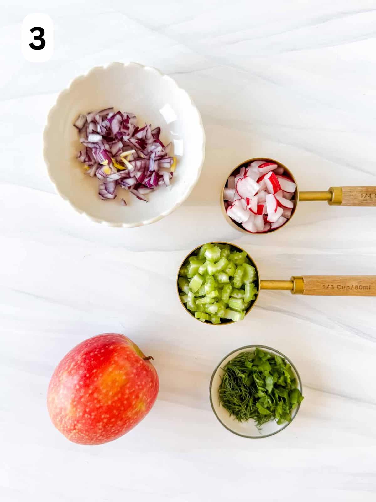 red apple and bowls of celery, radishes, red onion, dill and parsley labelled number three.