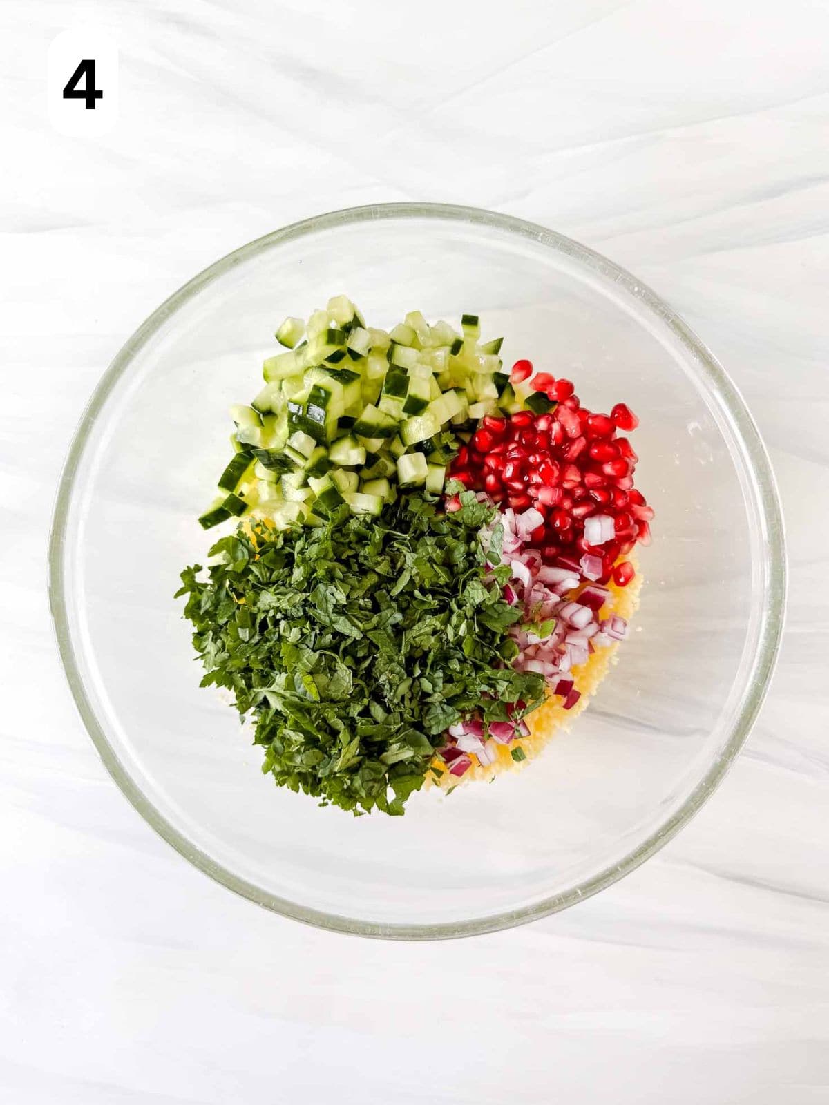 couscous, fresh mint leaves, fresh parsley, diced cucumber, diced red onion and pomegranate seeds in a glass bowl labelled number four.