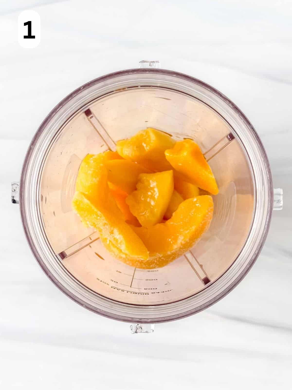frozen peach slices and apple juice in a blender cup labelled number one.