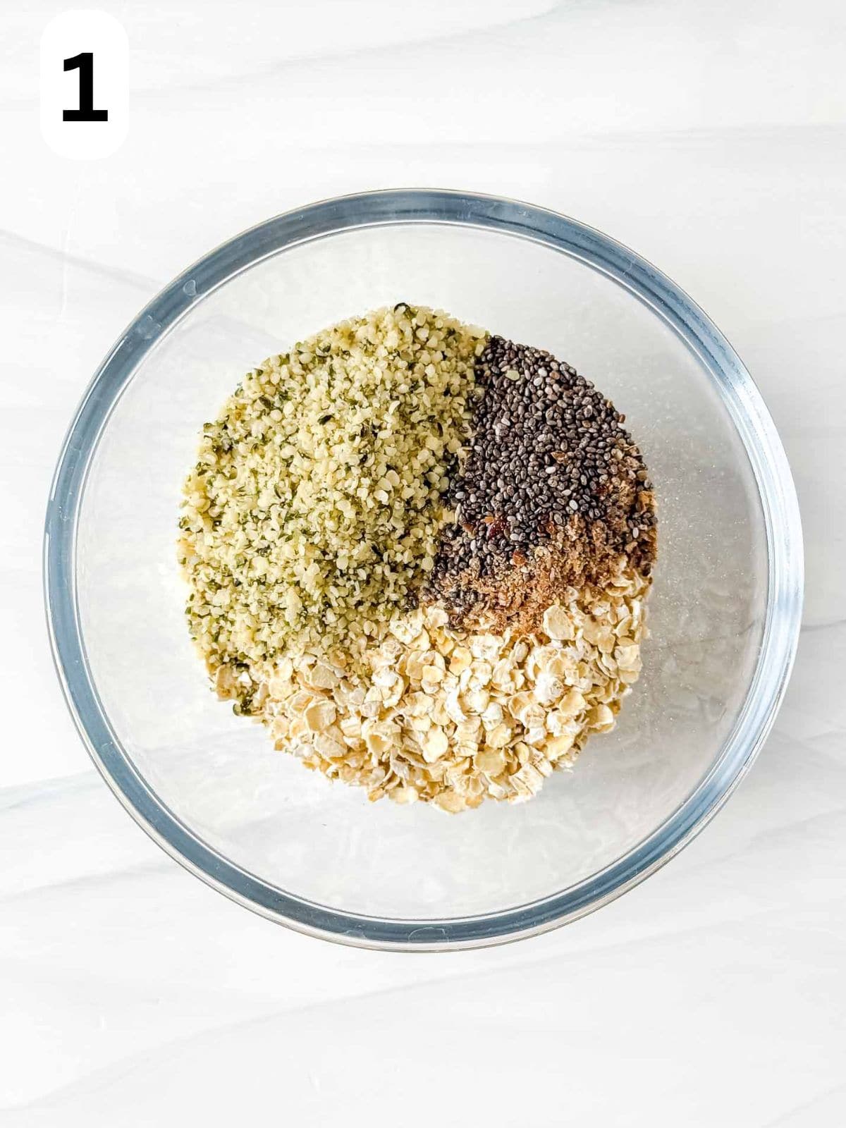 oatmeal, hemp seeds, chia seeds and ground flaxseed in a glass bowl labelled number one.