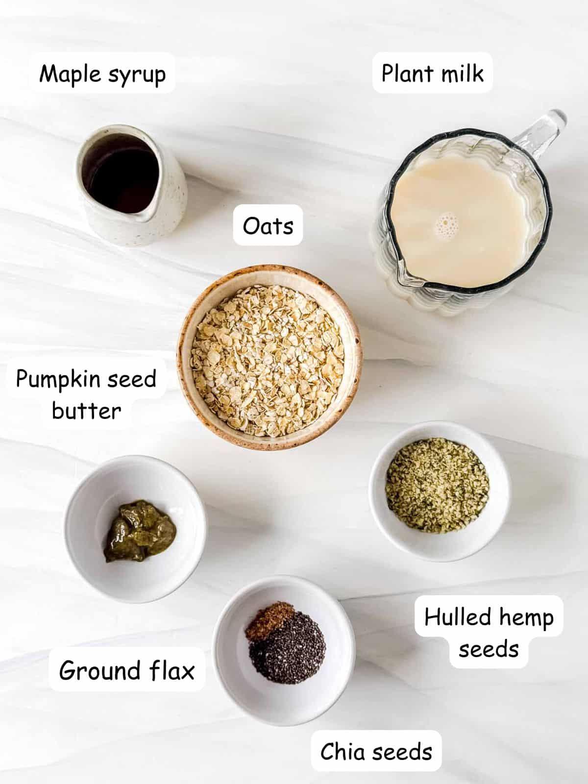individually labelled bowls of oats, chia seeds, ground flax, hulled hemp seeds, pumpkin seed butter and maple syrup.