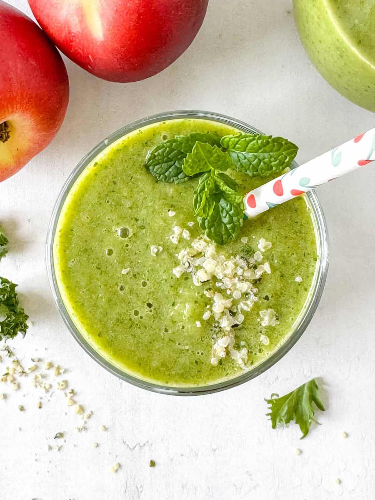 low histamine smoothie in a glass next to fruit, topped with mint leaves and hemp seeds.