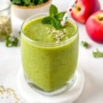 low histamine smoothie in a glass next to leafy greens, fruit and hemp seeds.