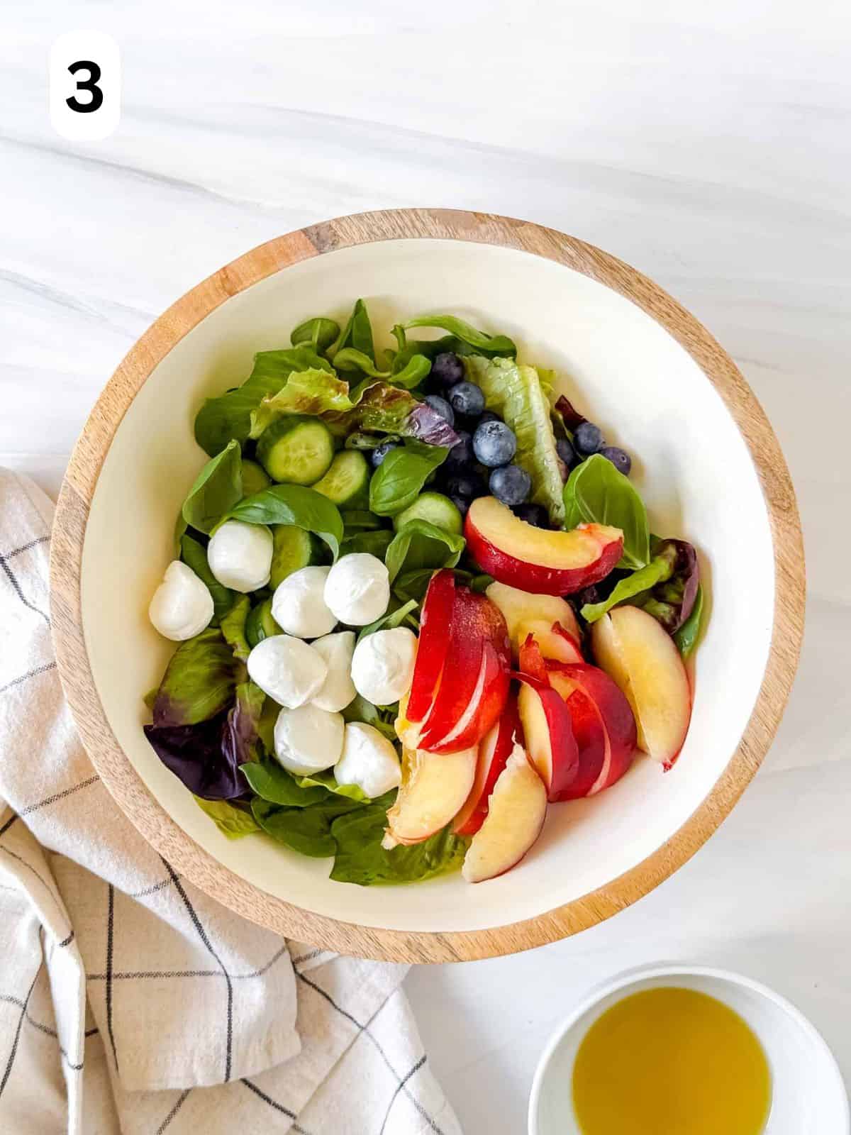 lettuce leaves, mini mozzarella balls, blueberries and sliced nectarines in a large bowl labelled number three.