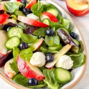 nectarine salad with mozzarella, cucumber and basil on a plate.