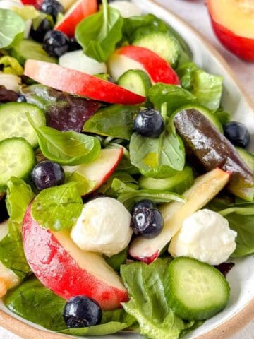 nectarine salad with mozzarella, cucumber and basil on a plate.
