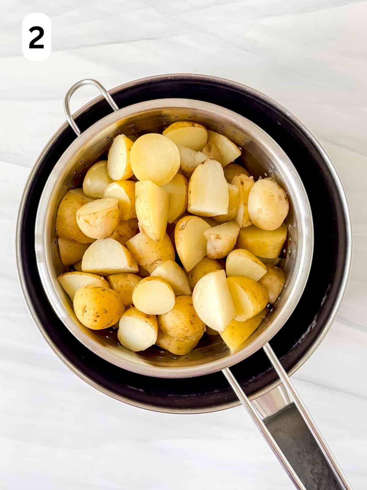 cooked new potatoes in a colander labelled number two.