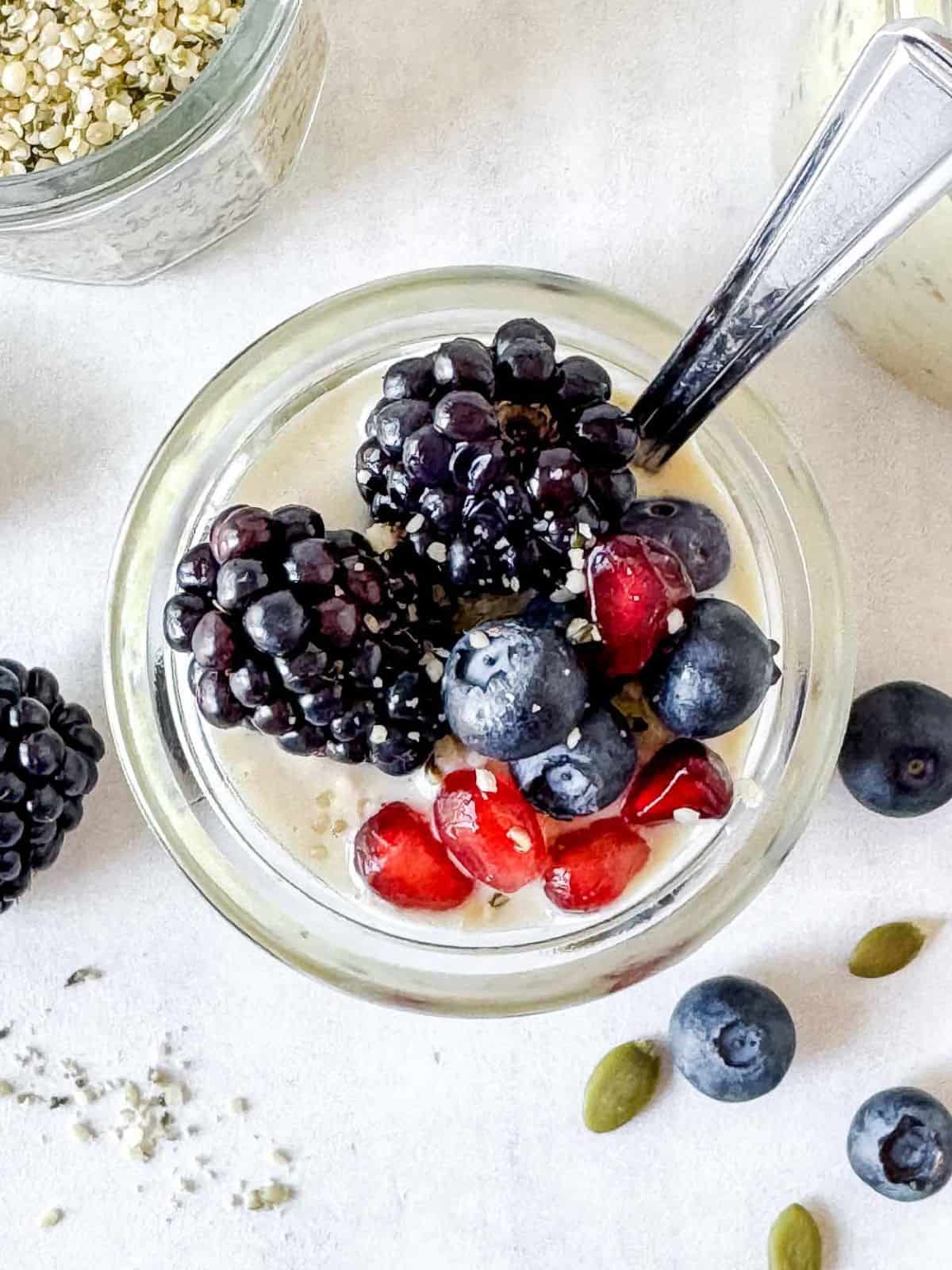 overnight oats with hemp seeds in a glass jar with a spoon in it.